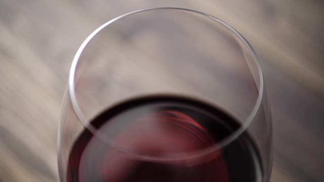 高档红酒。美味的葡萄酒，由美味的红葡萄制成的酒杯，在桌子上的棕色背景。摄像头向下移动。缓慢的运动。近距离视频下载