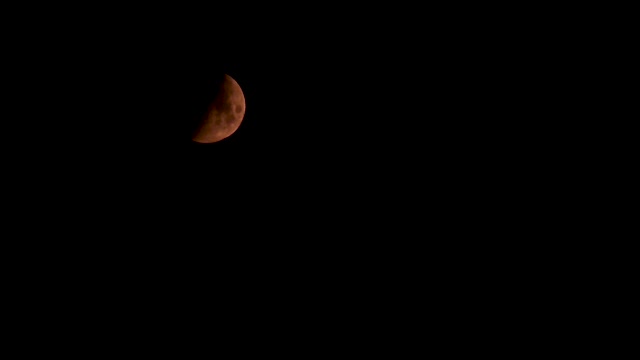 半颗红色的月亮在黑色的天空下视频素材