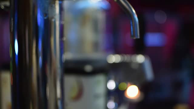 特写的观点，一个酒保的手倒啤酒到玻璃从水龙头在一个酒吧视频素材