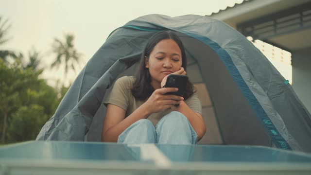 在家里的帐篷里用智能手机微笑的快乐女人视频素材