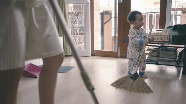 小男孩在用扫帚打扫地板视频下载