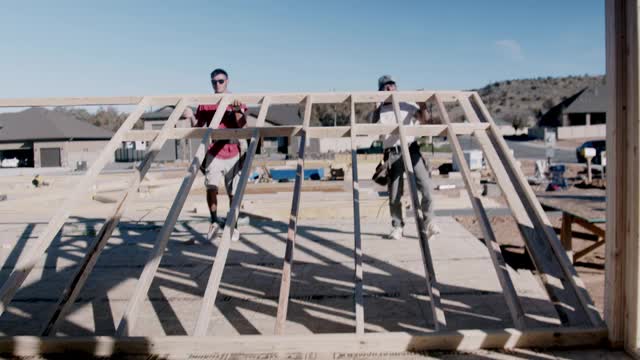 一群木匠建筑工人正在一个住宅建筑工地上架起一堵木墙视频下载