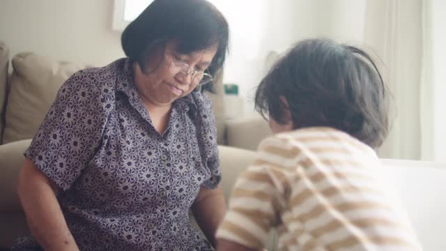 一位老年妇女正在家里的客厅里和她的孙子玩。视频素材