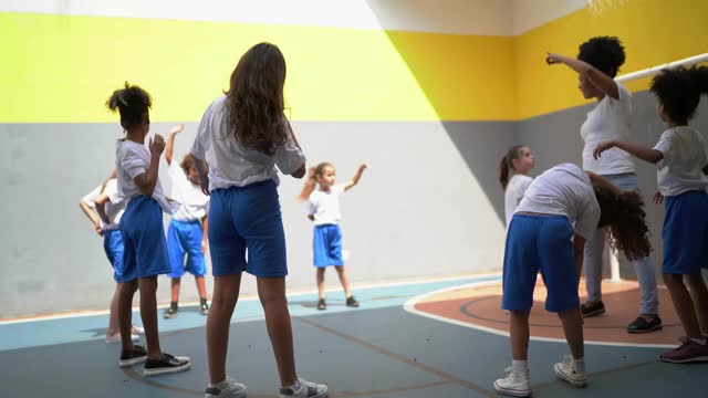 体育活动老师在学校和学生们一起伸展手臂视频下载