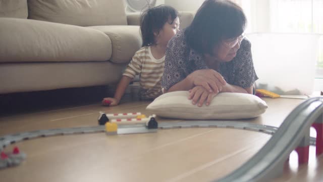 一位老年妇女正在家里的客厅里和她的孙子玩。视频素材