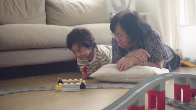 奶奶和孙子在家里一起玩玩具。视频素材