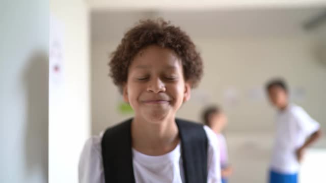 一个快乐的小学生在学校走廊里的肖像视频素材