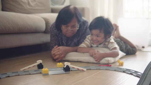 一位老年妇女正在家里的客厅里和她的孙子玩。视频下载