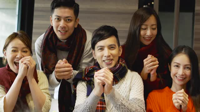 春节快乐，年轻的一群人在餐厅用祝贺的手势打招呼视频购买