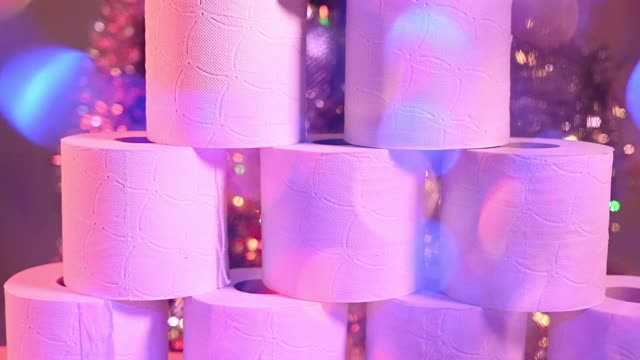 许多卫生纸角色的特写。在模糊的背景中，有一棵装饰着彩灯的圣诞树。镜头的运动。视频下载