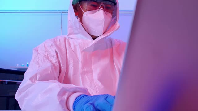 身穿个人防护服的科学家在实验室进行COVID - 19疫苗研究。视频素材