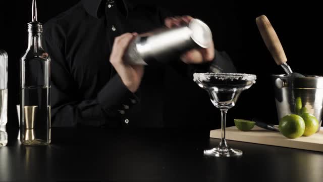 典型的玛格丽塔鸡尾酒。调酒师在黑色背景的波士顿摇酒器中摇晃鸡尾酒成分。玛格丽塔准备的概念。IBA官方鸡尾酒。时间来喝。广角镜头视频素材