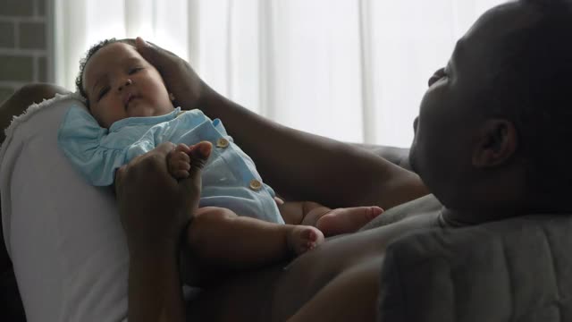 非洲父亲抱着4个月大的儿子在家预防冠状病毒或Covid-19流行的幸福家庭。家人时刻的概念。视频素材