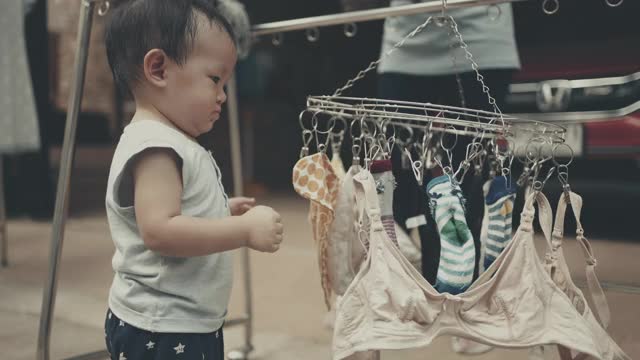 小男孩帮妈妈晾洗好的衣服视频下载