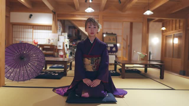 穿着Furisode和服的年轻女子坐在高跟鞋上，在日本的榻榻米房间鞠躬视频下载