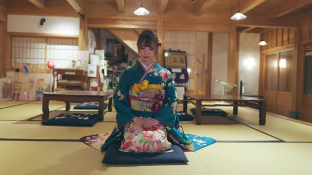穿着Furisode和服的年轻女子坐在高跟鞋上，在日本的榻榻米房间鞠躬视频素材