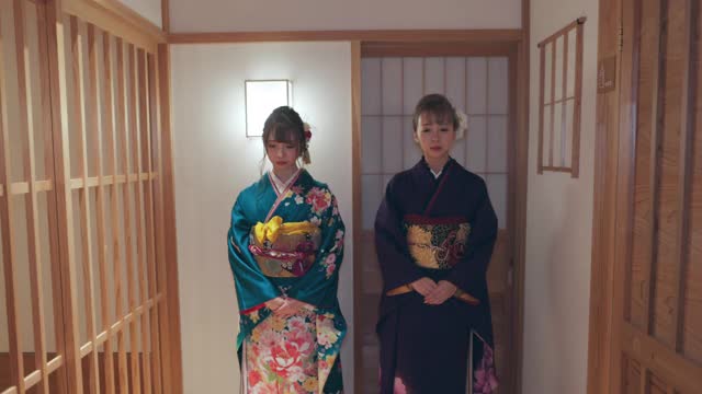 两个穿着Furisode和服的年轻女子一起走在日本旅馆的走廊上视频素材
