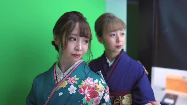 身着Furisode和服的年轻女子在“Purikura”照片贴纸摊上为“Seijin Shiki”成人礼拍照视频素材