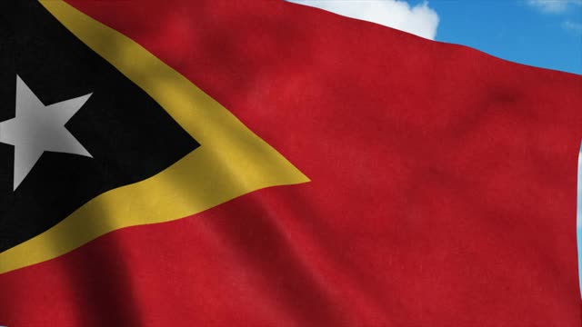 东帝汶国旗在风中飘扬，蓝天背景。4 k视频素材