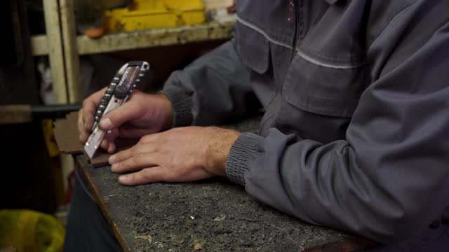 一个修鞋匠在他的作坊里用手术刀做出合适的形状视频下载
