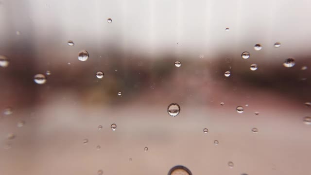 巨大的雨滴落在窗户玻璃上视频素材