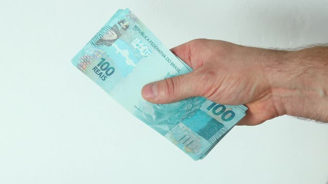 巴西货币，100雷亚尔的钞票叠好，在你手中数视频素材