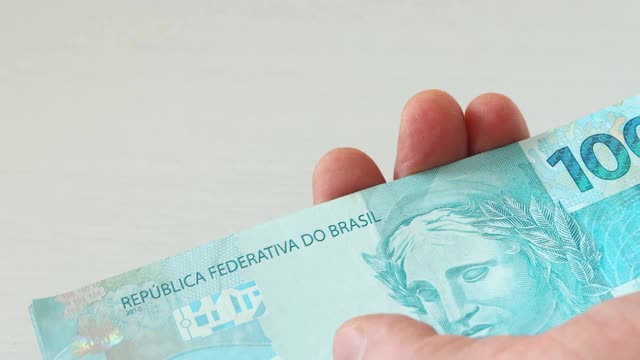 巴西货币，100雷亚尔的钞票叠好，在你手中数视频下载