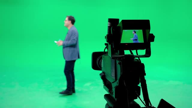 摄像播音员在一个专业的绿屏演播室里跟在后面。影视产业视频素材