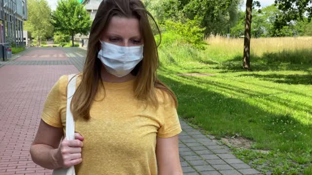 戴防毒面具的妇女走在人行道上视频素材