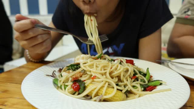 4K，亚洲女孩捻意大利面在白色的盘子和吃视频素材