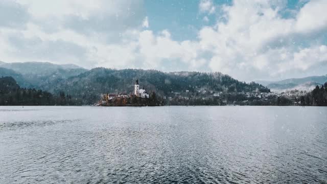 航拍的一个白雪皑皑的秋日湖泊，前景中有一座教堂视频下载
