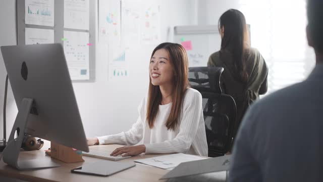 亚洲女商人与她的同事在办公室用电脑工作视频素材