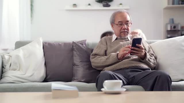 4K超高清倾斜:一个亚洲女孩和她的爷爷玩躲猫猫，而他正在用他的智能手机。视频下载