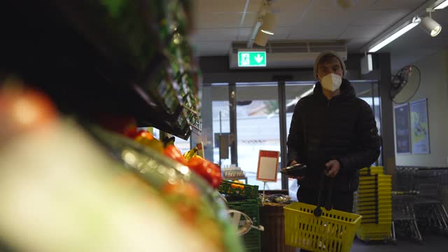 一名戴着面具在商店挑选水果的男子视频素材