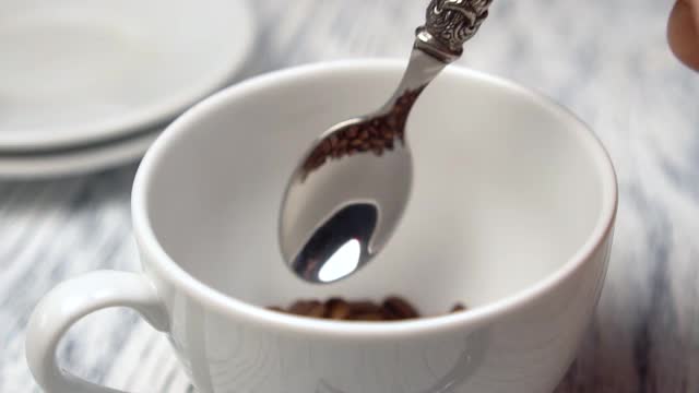 用闪亮的勺子盛着阿拉比卡优质生物咖啡豆。木桌上放着一只白色的杯子视频下载