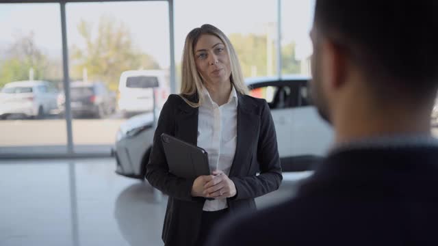 汽车销售员与男顾客在汽车经销商交谈视频下载