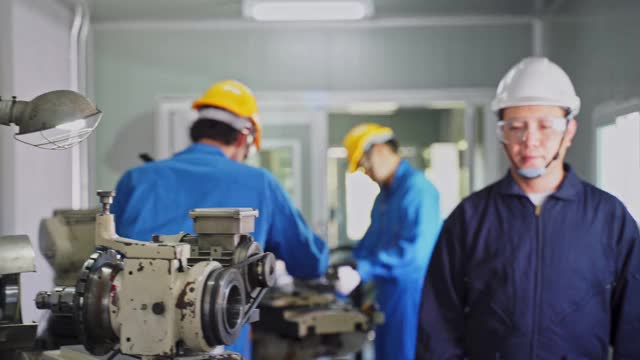 亚洲机械工人在铣床上工作。技术人员在操作机器时戴上防护眼镜和安全帽，以确保安全。男人的肖像交叉手臂看着相机视频素材