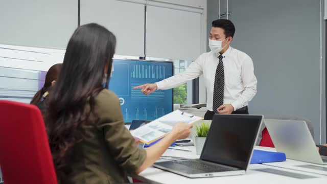 亚洲团队的商务人士在办公室工作与新的正常的社会距离的生活理念。男性和女性在一起时佩戴防护口罩，保持距离，防止冠状病毒感染视频素材