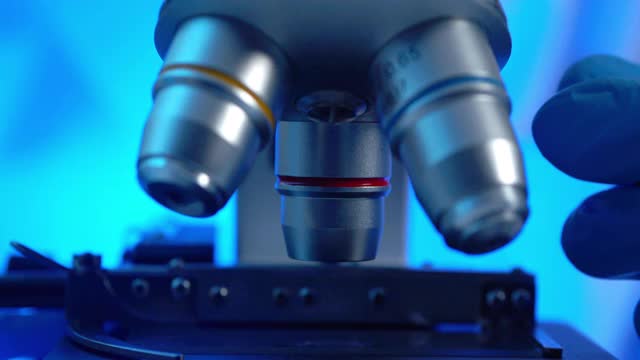 从病毒到实验室技术研究到冠状病毒或Covid-19的显微镜聚焦特写镜头。卫生保健研究人员在教室或科学实验室工作到很晚。科学家使用显微镜的概念。视频下载