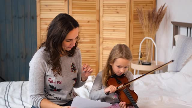 一个女人教小女孩在室内拉小提琴视频素材