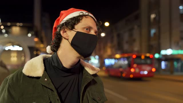 一名男子在头发上戴着圣诞老人帽。在一场流行病中庆祝新年。视频下载