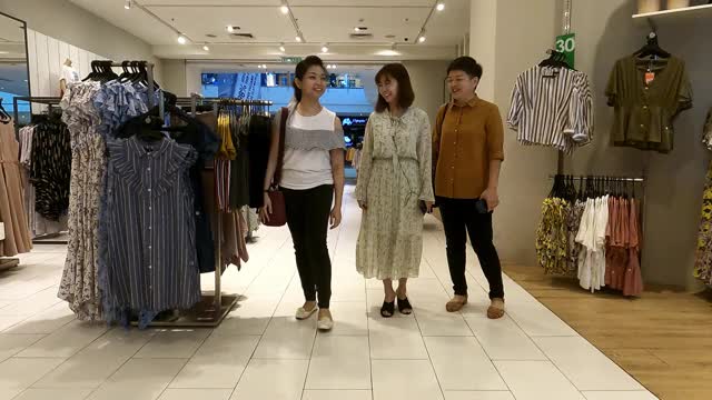 亚洲华人女性在服装店看着镜子挑选衣服视频下载