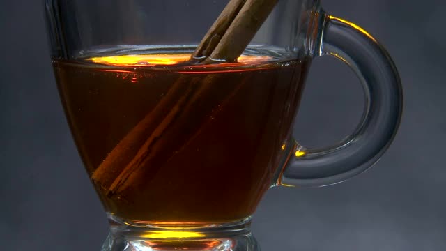茶与肉桂棒搅拌在一个玻璃杯靠近视频下载