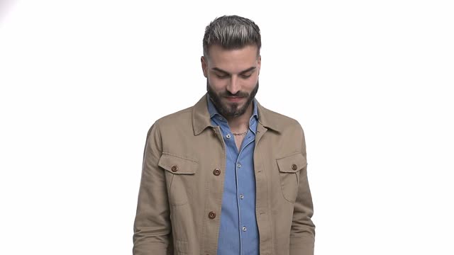 一个穿着米色夹克的休闲青年在工作室里做拇指向上的手势和微笑孤立的白色背景视频素材