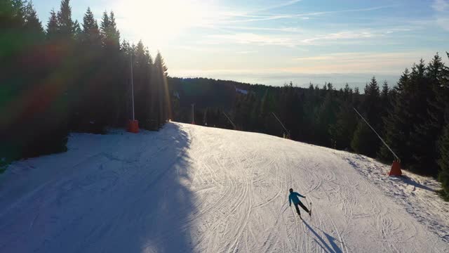 在一个阳光明媚的日子里，一名男子在滑雪时，无人机飞过滑雪坡视频下载