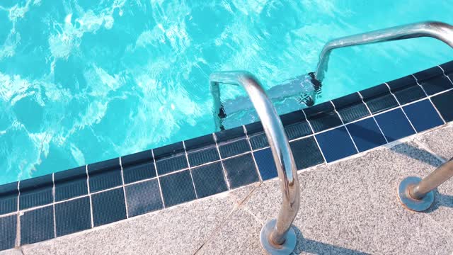 在阳光明媚的日子里，入口游泳池的梯子和闪亮的游泳池水视频下载