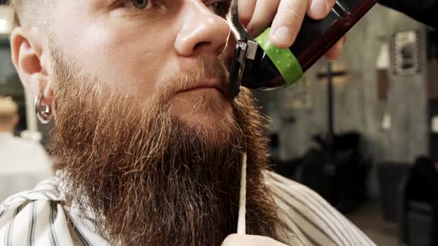 理发师剪掉客户的小胡子和胡子，梳理他的头发。视频下载