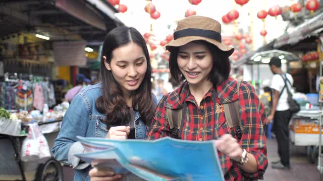 两个亚洲游客朋友在使用城市指南中的地图视频素材