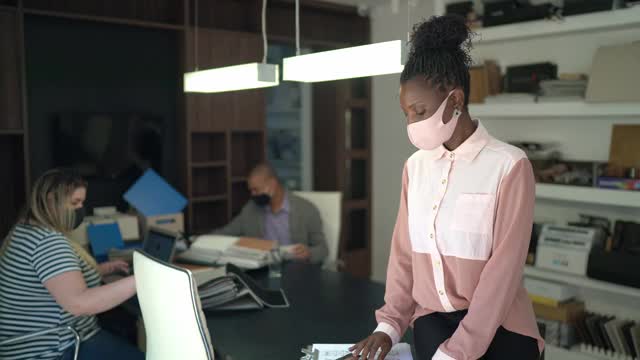 一幅女商人戴着面具在办公室里的肖像，背景是同事视频素材