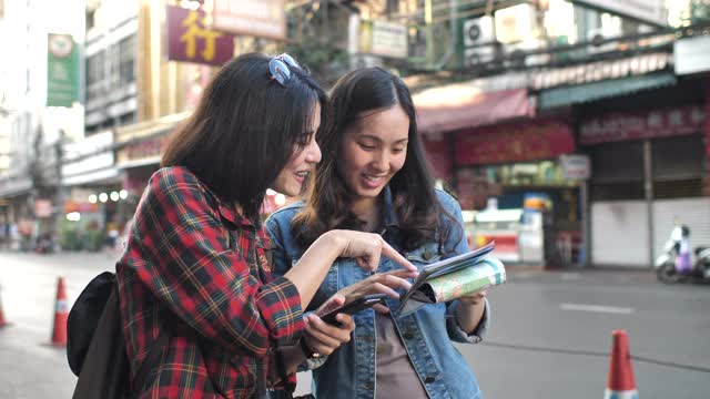 两个亚洲游客朋友在使用城市指南中的地图视频素材